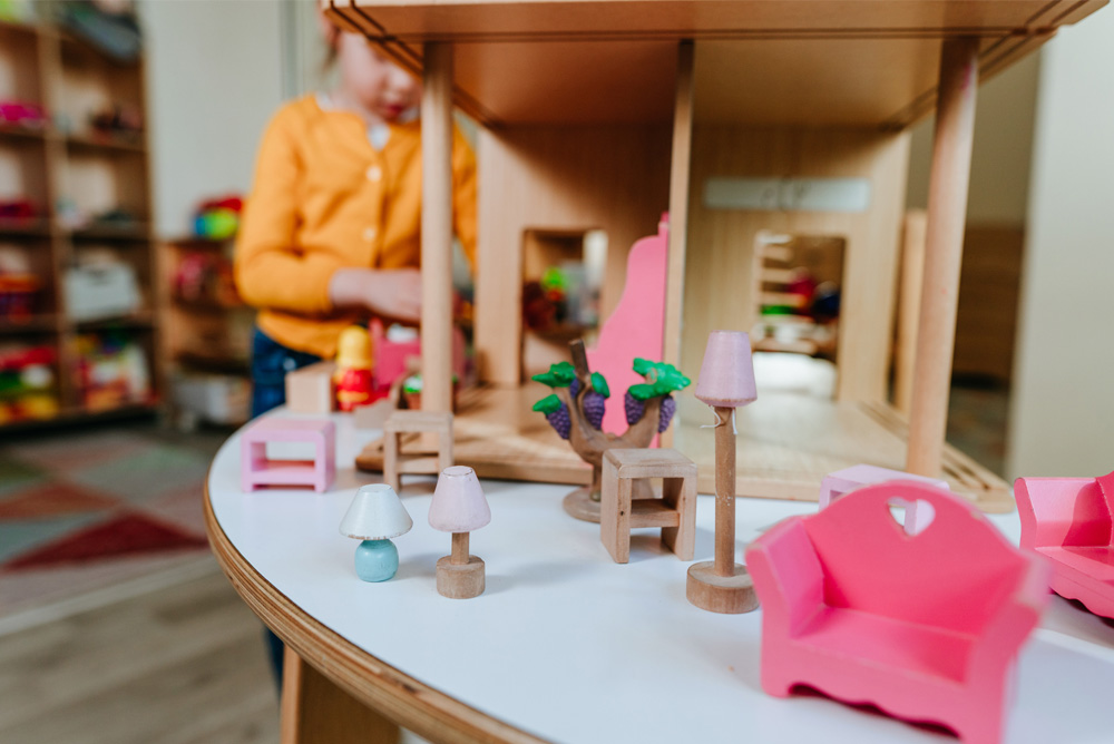 Little girl playing with wooden house at kindergarten stock photo